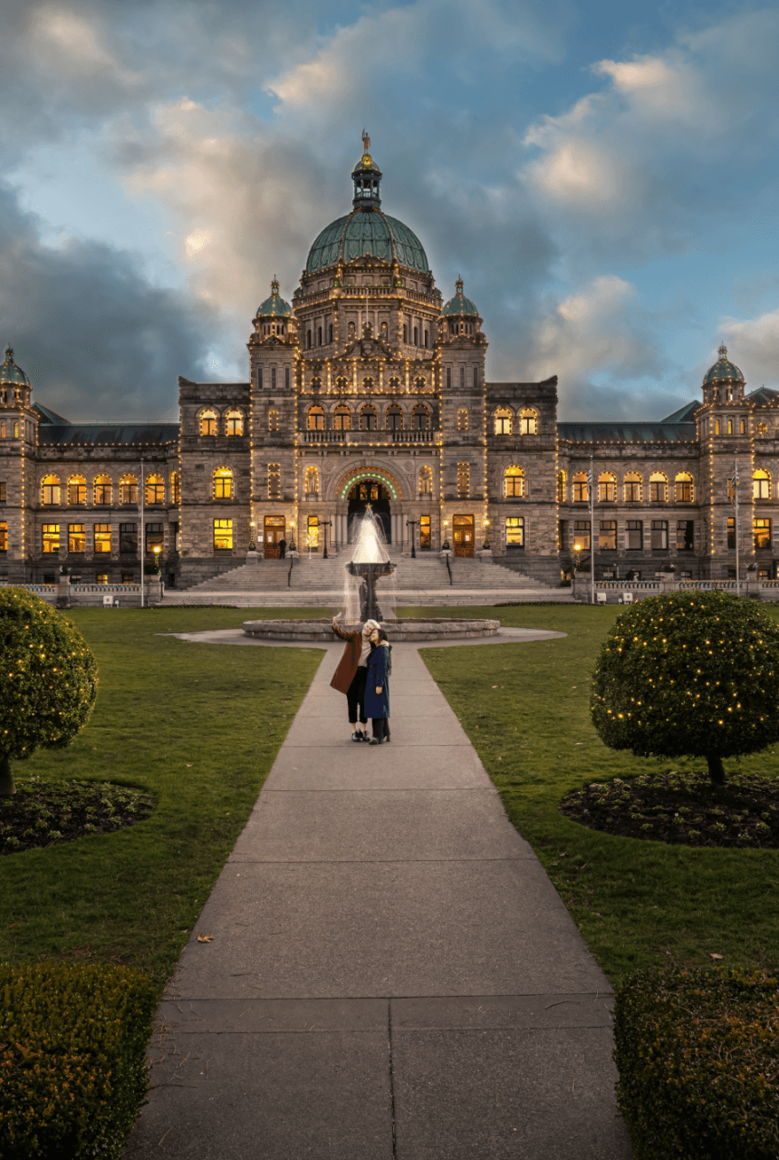 A couple walking in front of the Victoria Parliament building