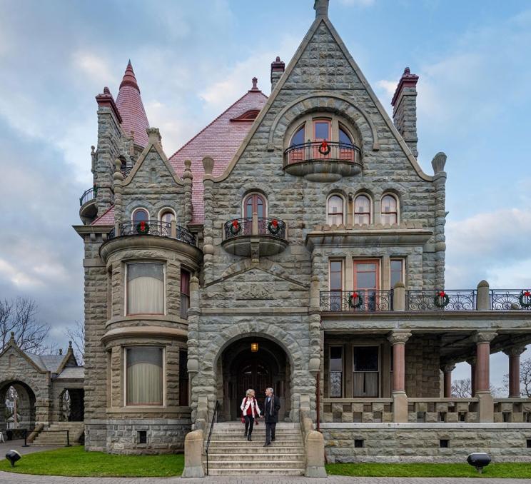 A couple walks hand-in-hand down the steps of Craigdarroch Castle Historic House & Museum during the holiday season in Victoria, BC