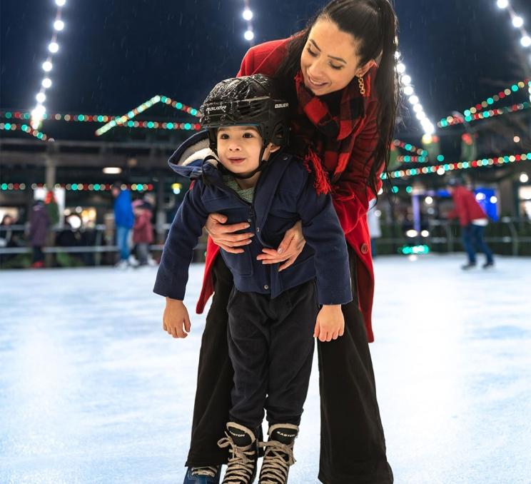 A woman teaches her son how to ice skate on the outdoor skating rink at The Butchart Gardens in Victoria, BC
