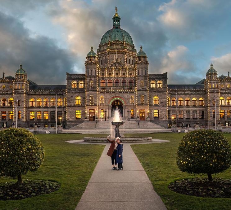 A couple takes a selfie outside of the BC Parliament Buildings when it is adorned with holiday lights in Victoria, BC
