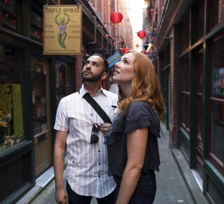 A man in a white shirt and a woman in blue examine the architecture in Fan Tan Alley in Victoria, BC's Chinatown