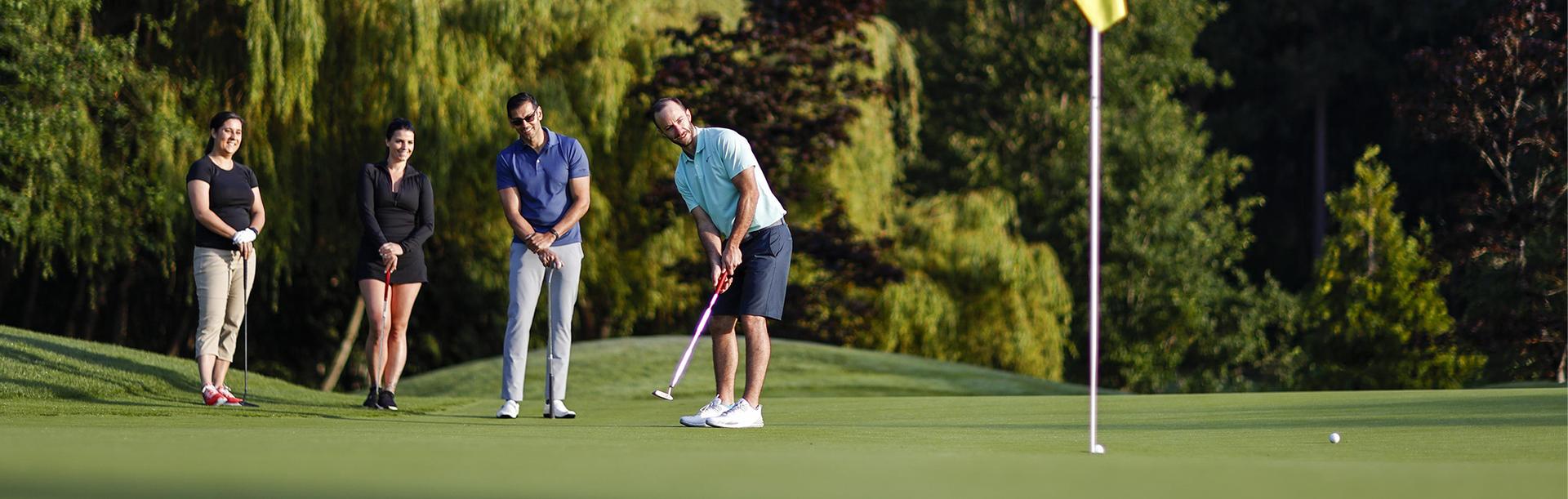 A golfer wearing blue putts while on a green at a Victoria, BC golf course