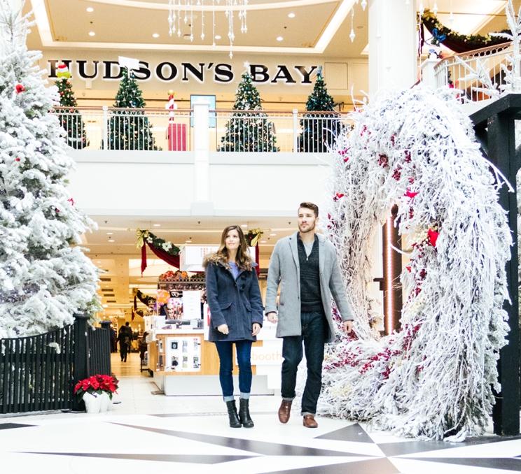 A couple walks through a Christmas display at the Bay Centre Shopping Centre in Victoria, BC