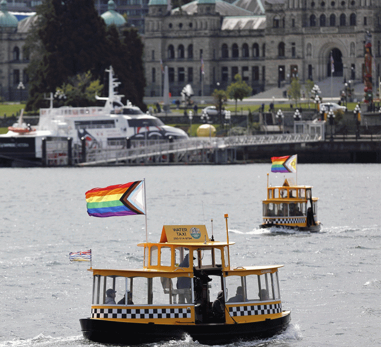 Victoria Harbour Ferries flying Pride flags sailing across Victoria, BC's Inner Harbour