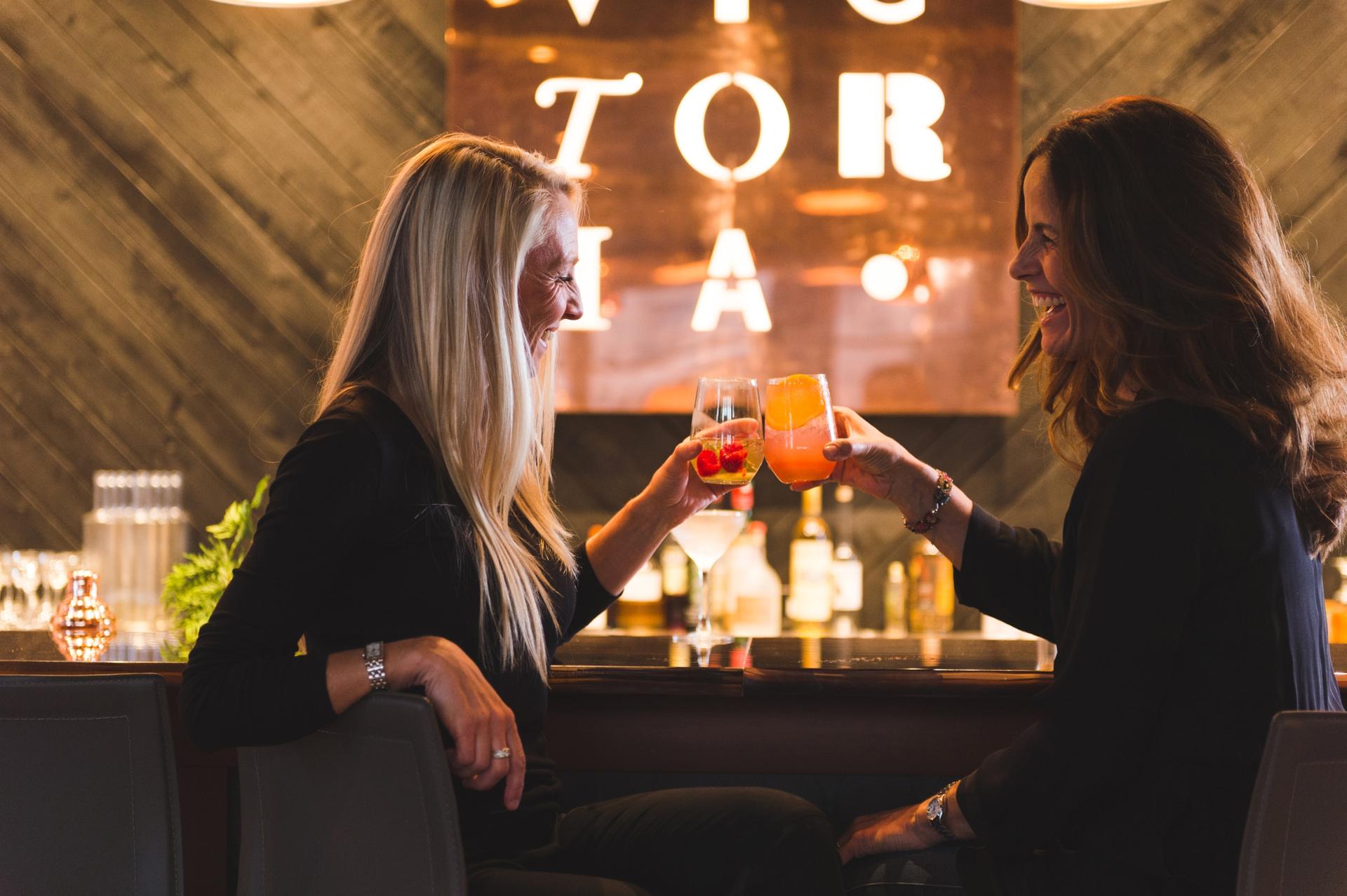 Two women celebrate over cocktails at Victoria Distillers in Victoria, BC