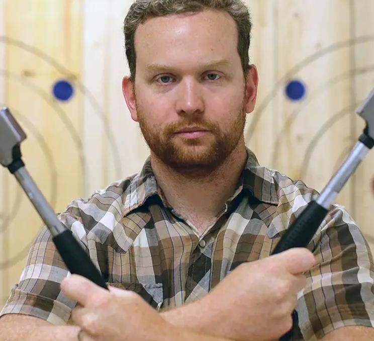 A man poses with a pair of axes at Axe & Grind in Victoria, BC