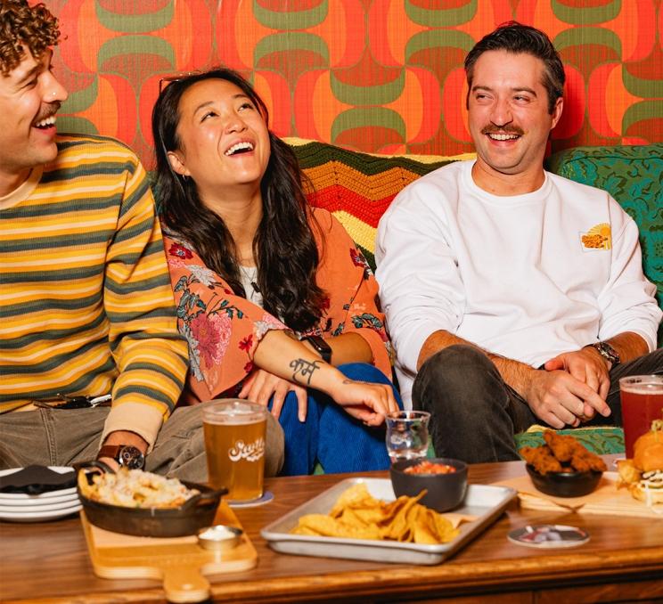 A group of friends enjoying snacks on drinks on a couch at Swift Brewing in Victoria, BC