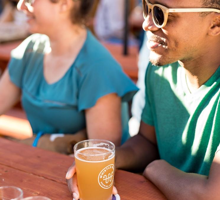 A man enjoys a glass of beer on the patio at Whistle Buoy Brewing in Victoria, BC