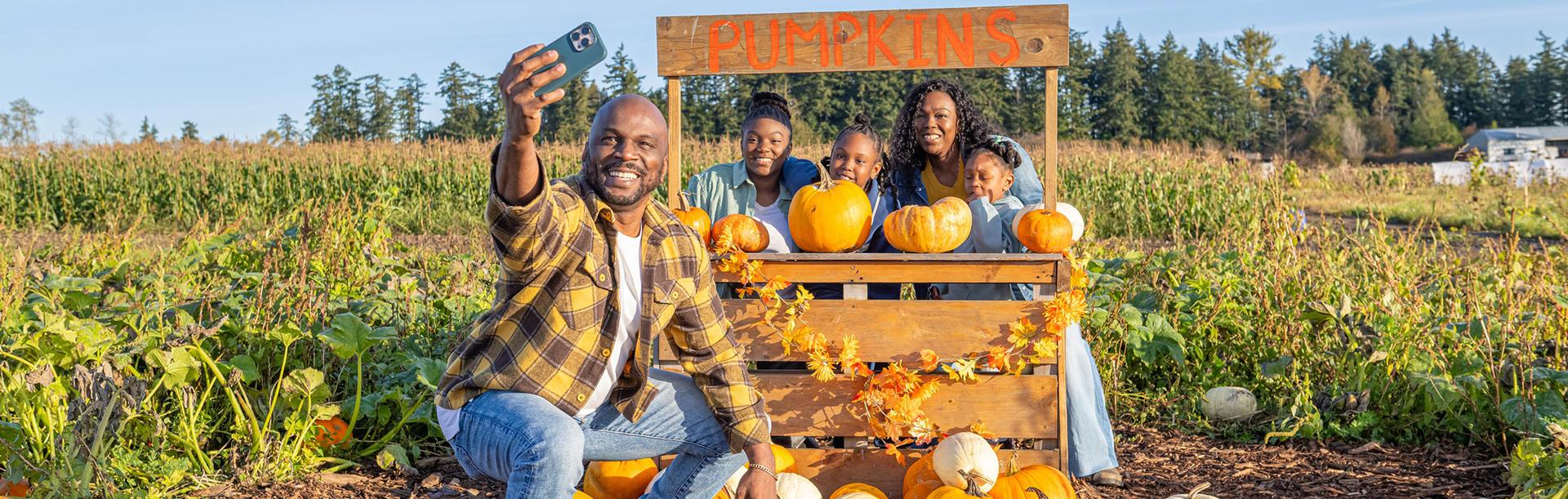 A young family poses for a selfie in a pumpkin patch in Victoria, BC