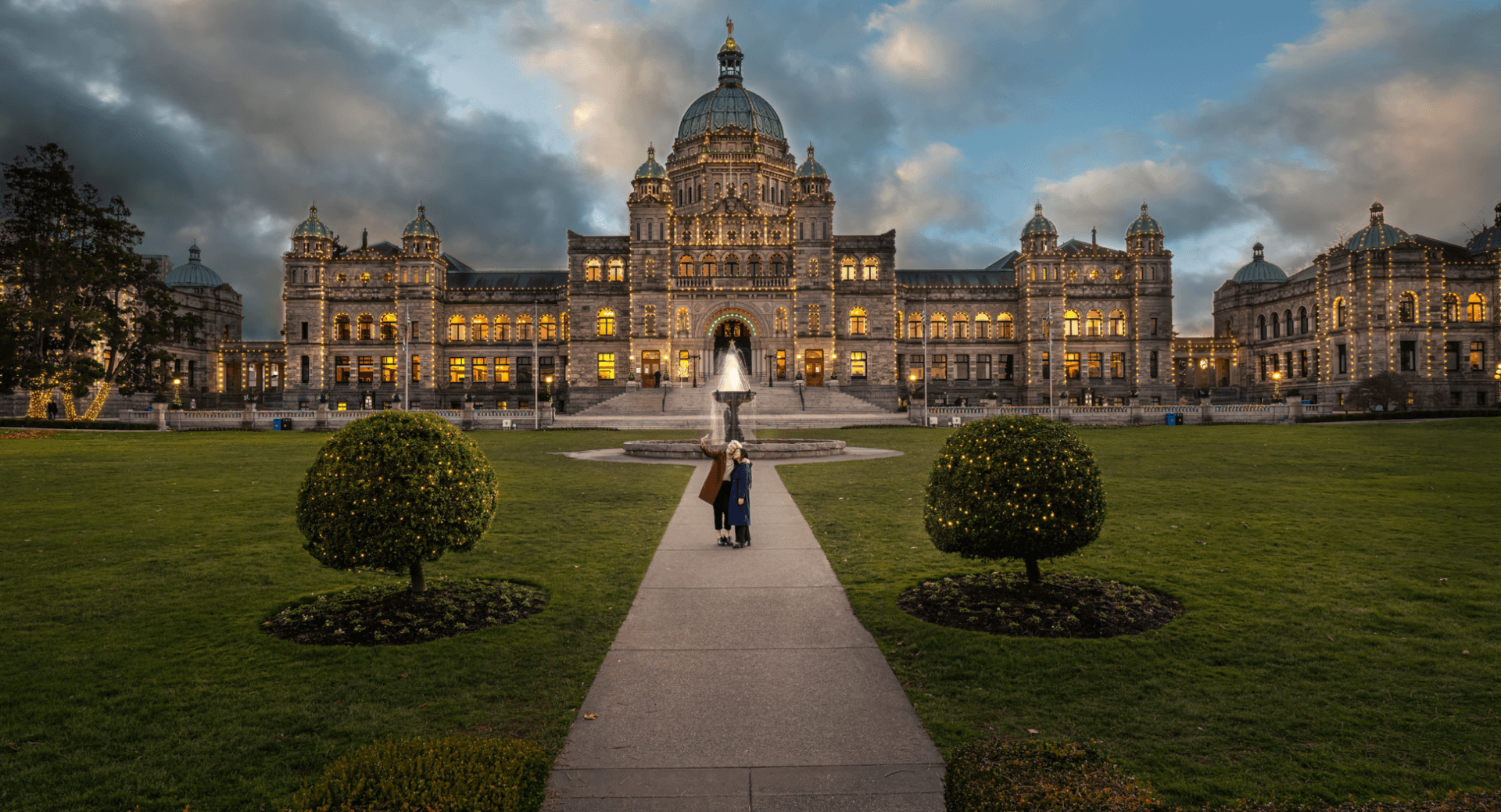 A couple walking in front of the Victoria Parliament building