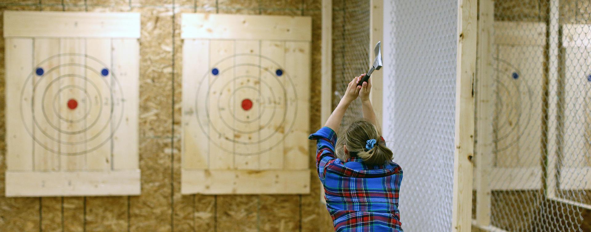 A woman throws an axe at a target at Axe and Grind