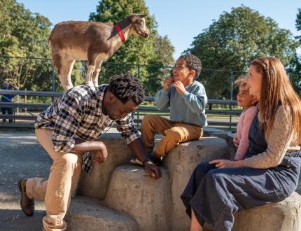 a smiling family enjoying the petting zoo at Beacon Hill Park