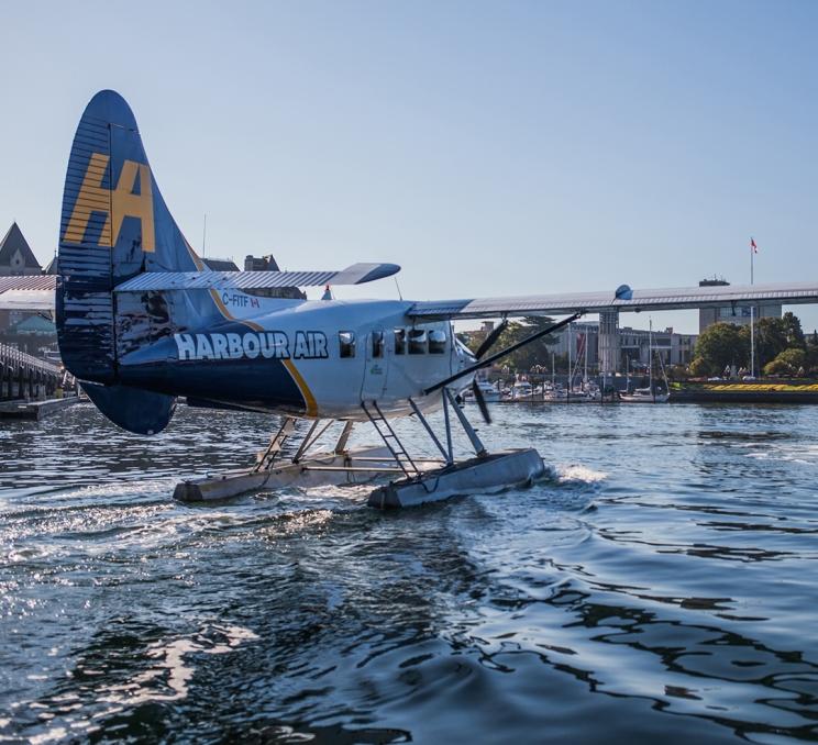 A blue and white Harbour Air seaplane taxis across the water on Victoria BC's Inner Harbour