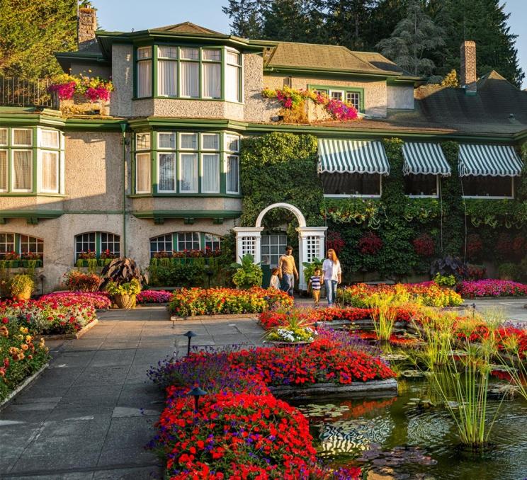 A young family walks through a courtyard adorned with red flowers in Victoria, BC