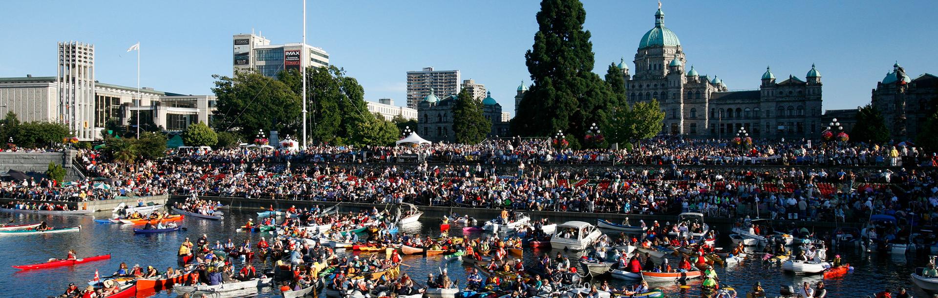 A crowd of onlookers watch Symphony Splash in Victoria BC's Inner Harbour with the BC Parliament Buildings in the background