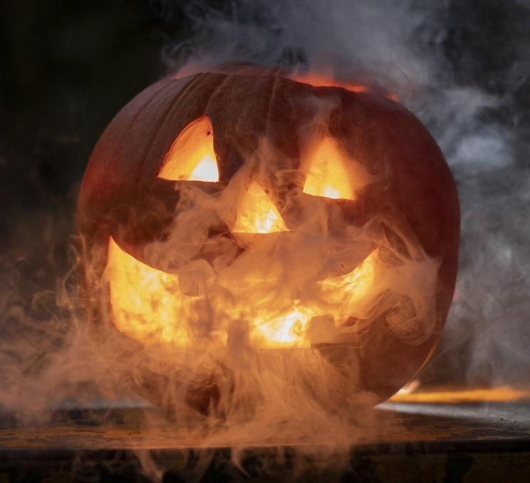 A jack-o-lantern sits surrounded by smoke