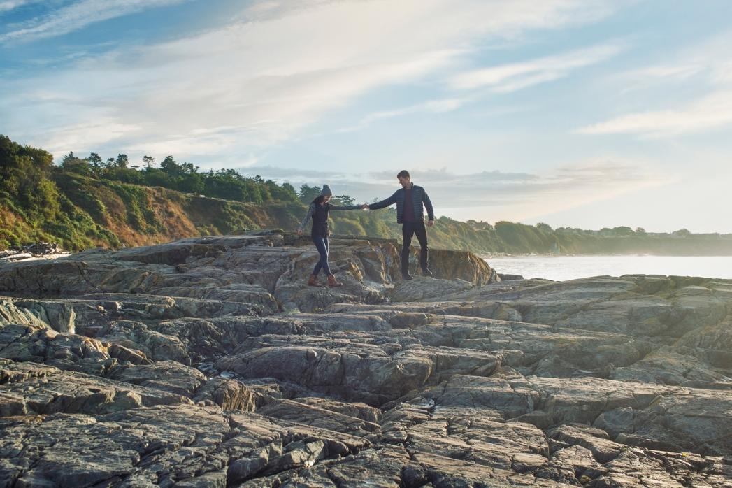 A couple walks along the rocks at Dallas Road Beach in Victoria, BC