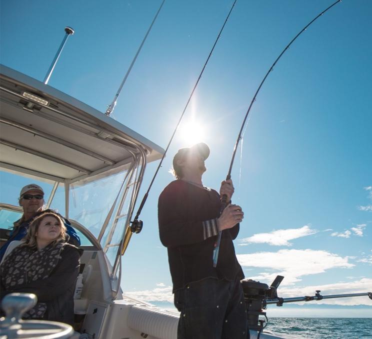 A man fishes off the back of a boat in the Salish Sea off the coast of Victoria, BC