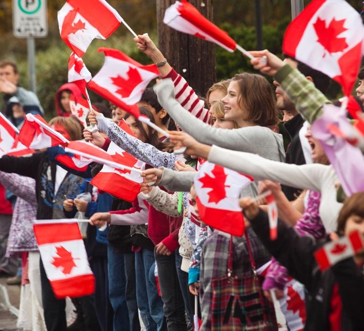 A group of people wave Canadian flags during Canada Day celebrations in Victoria, BC