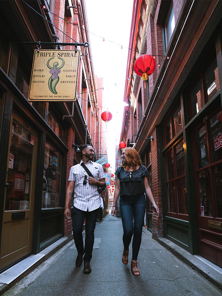 A couple walks down Fan Tan Alley, Canada's narrowest street, in Victoria, BC