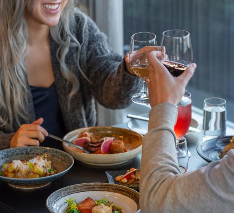 A couple toasts glasses of wine during a dinner at Aura in Victoria, BC