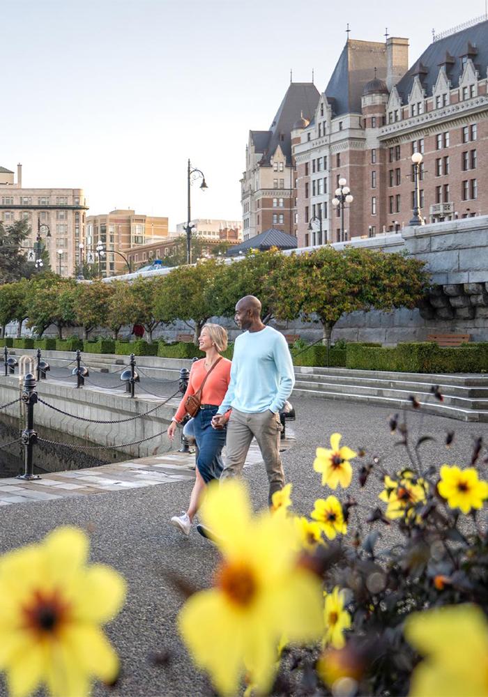A couple walks along Victoria BC's Inner Harbour