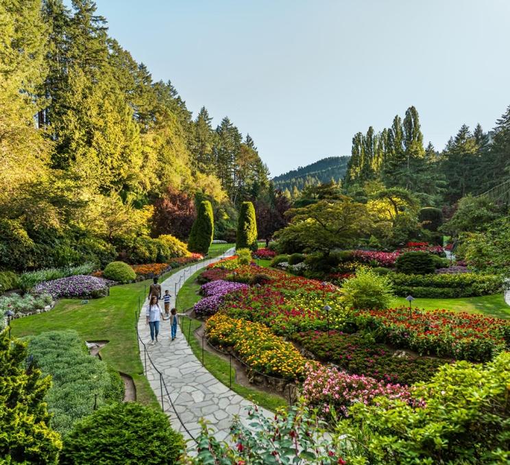 A young family walks through the Sunken Garden at The Butchart Gardens, A National Historic Site of Canada, in Victoria, BC