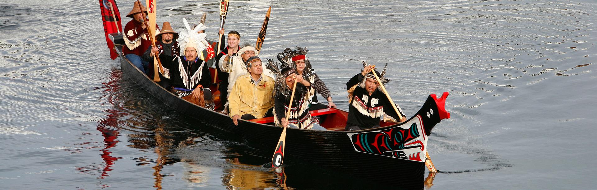 Indigenous people paddle a canoe through the Inner Harbour in Victoria, BC