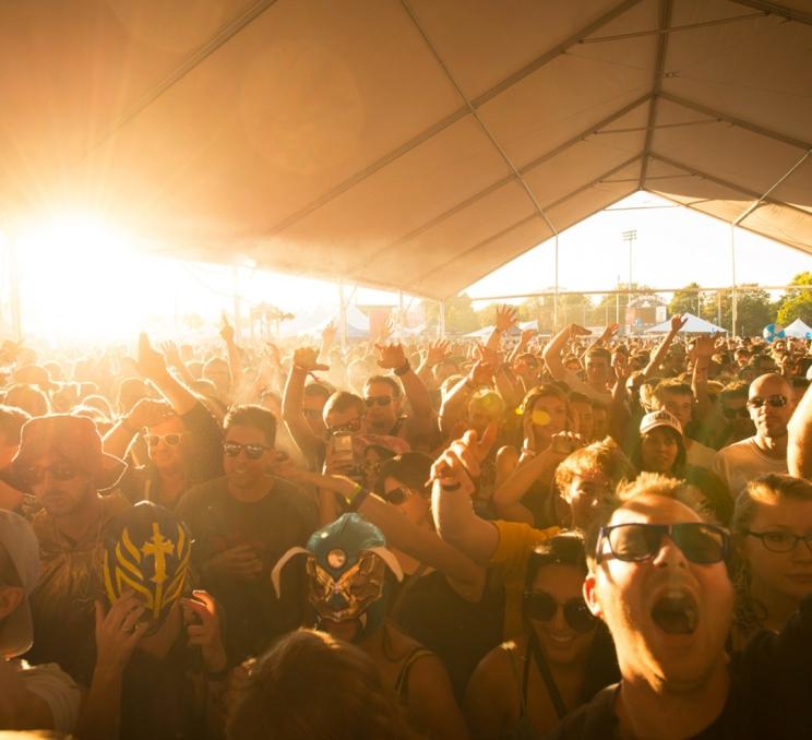 A crowd cheers as they face the stage while the sun sets behind them at the Rifflandia Music Festival in Victoria, BC