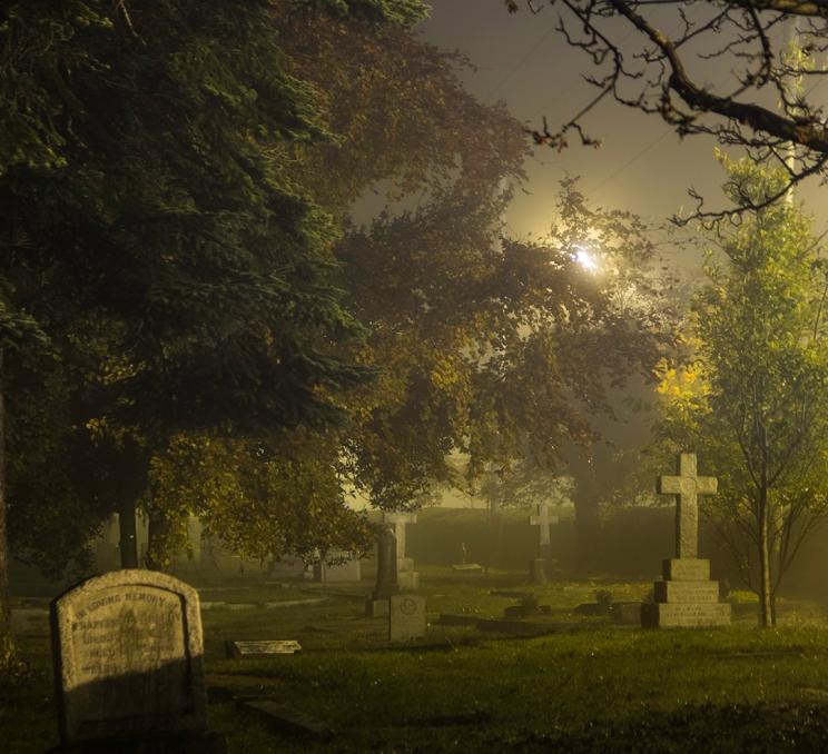Tombstones at Ross Bay Cemetery in Victoria, BC at night as the fog rolls in