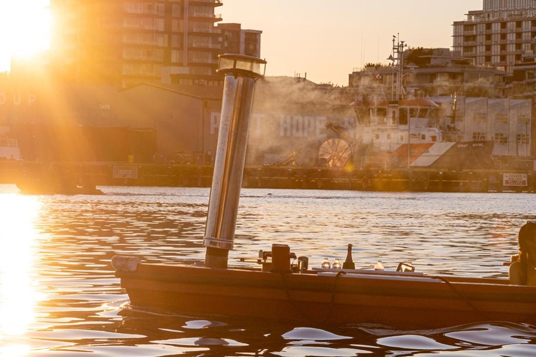 A couple riding a red hot tub boat through the Upper Harbour in Victoria, BC at sunset in Victoria, BC