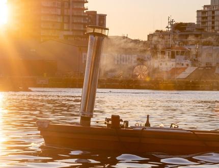 A couple riding a red hot tub boat through the Upper Harbour in Victoria, BC at sunset in Victoria, BC