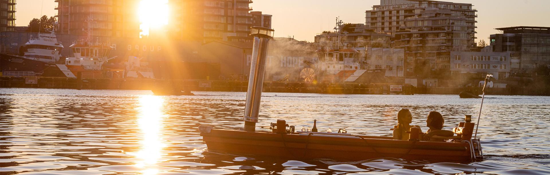 A couple riding a red hot tub boat through the Upper Harbour in Victoria, BC at sunset in Victoria, BC