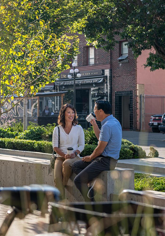 A couple drinks coffee along the boulevard in Victoria, BC