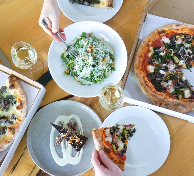 A spread of pizza and wine at FARO Handcrafted Pizza & Tasting Room at the Oak Bay Beach Hotel in Victoria, BC