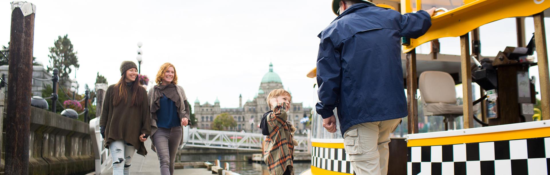 A young family boards a yellow harbour ferry in the Inner Harbour in Victoria, BC