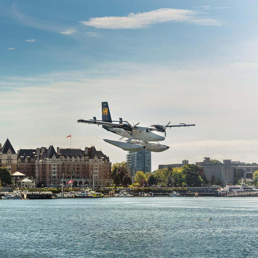 A Harbour Air Seaplanes flight prepares to land on the Inner Harbour with the Fairmont Empress hotel in the background in Victoria, BC
