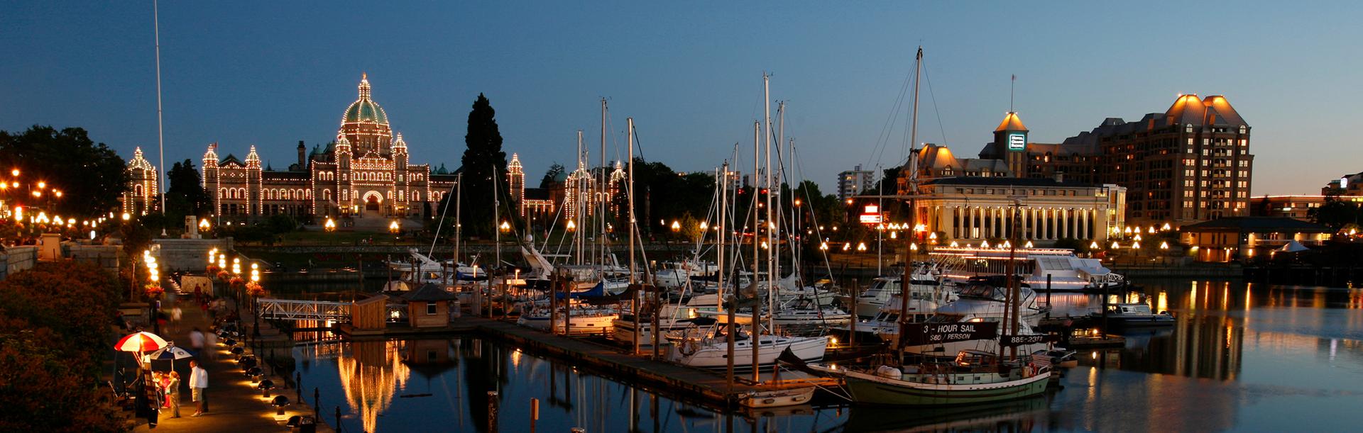 A view of the BC Parliament Buildings from across the Inner Harbour at dusk in Victoria, BC
