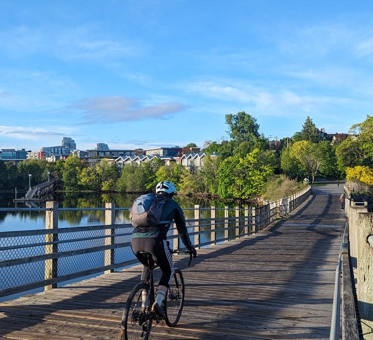 A cyclist rides a bike across the wooden planks of the Selkirk Trestle over the Gorge Waterway in Victoria, BC