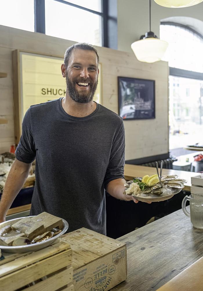 A man poses with a plate of oysters in Shuck Taylor's in Victoria, BC