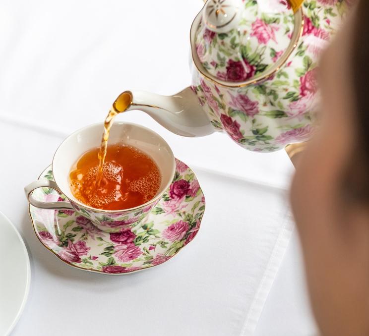 A woman pours a cup of tea our of a floral tea pot during Afternoon Tea service at the Pendray Tea House in Victoria, BC