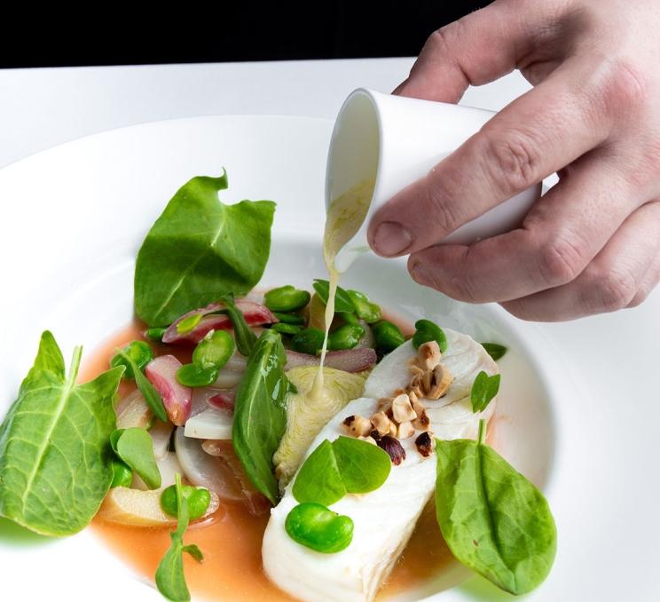 A seafood dish is finished with a sauce by a chef at The Courtney Room in Victoria, BC