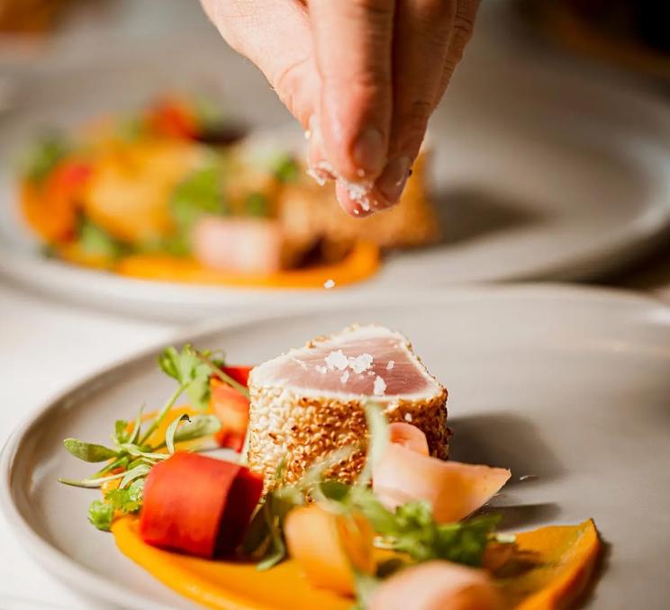 A chef sprinkles salt on a dish at Ugly Duckling in Victoria, BC