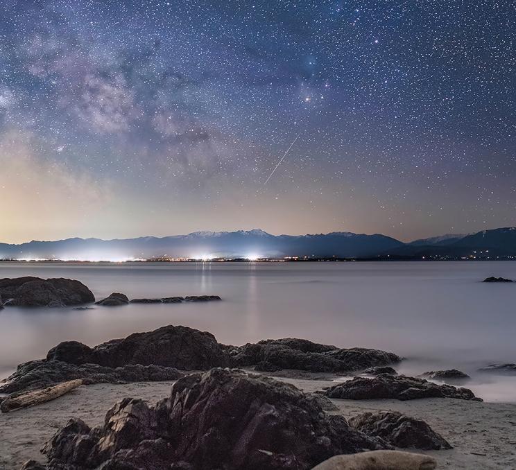 A meteor streaks through the sky above Aylard Farm in East Sooke Park, Greater Victoria, BC as seen from the beach