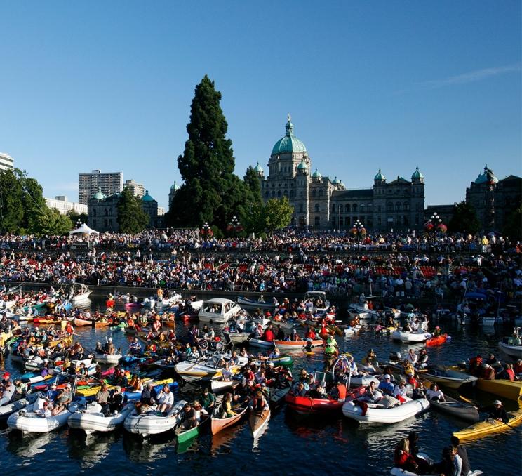 A crowd gathers along the Inner Harbour with onlookers on shore and on the water in boats to watch Symphony Splash, a classical music festival, in Victoria, BC.
