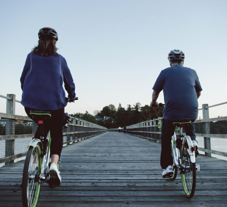 A couple rides bikes along the Selkirk Trestle in Victoria, BC