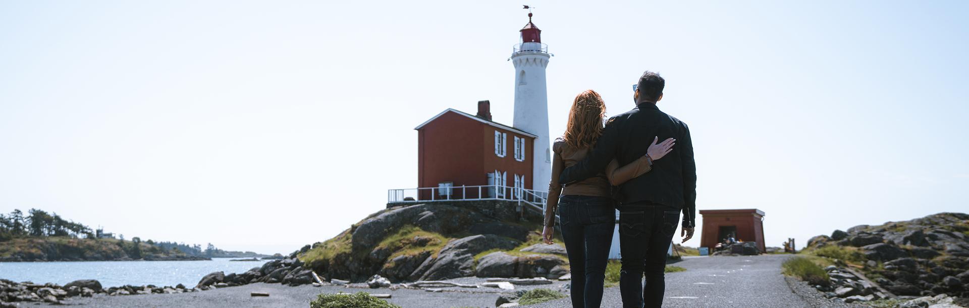 A couple walks out toward Fisgard Lighthouse in Victoria, BC
