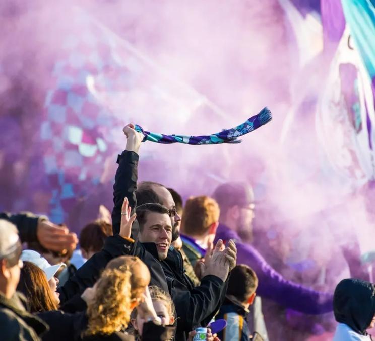 Pacific FC supporters wave their banners and let off purple smoke at a soccer game in Greater Victoria, BC