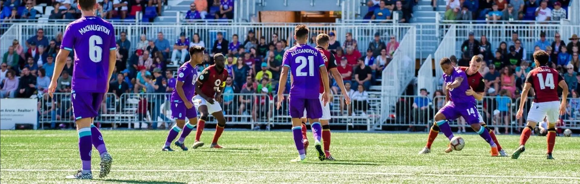 Pacific FC, a Greater Victoria based soccer team, dressed in their purple kit, plays a soccer game in Greater Victoria, BC while a crowd cheers
