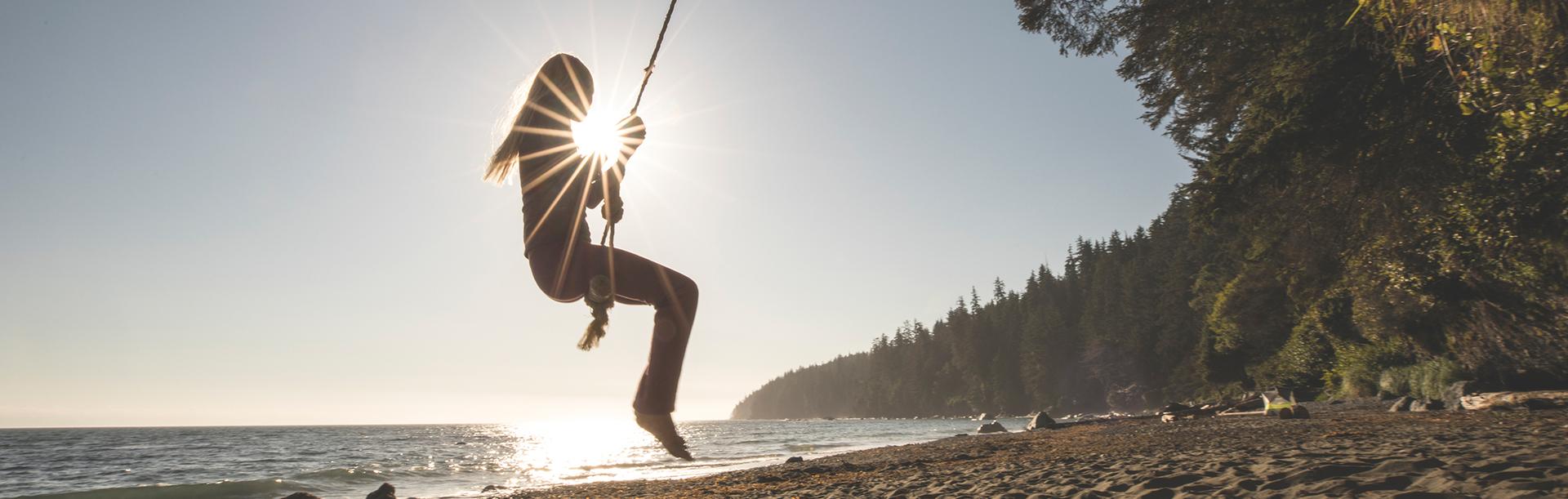 A woman swings on a rope swing at Mystic Beach in Greater Victoria, BC